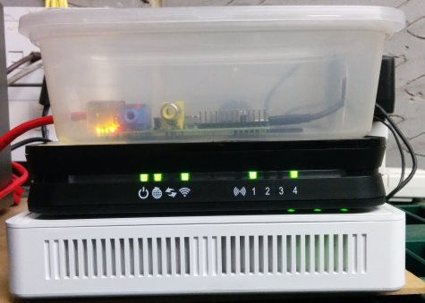Raspberry Pi in a takeway container on top of random network equipment